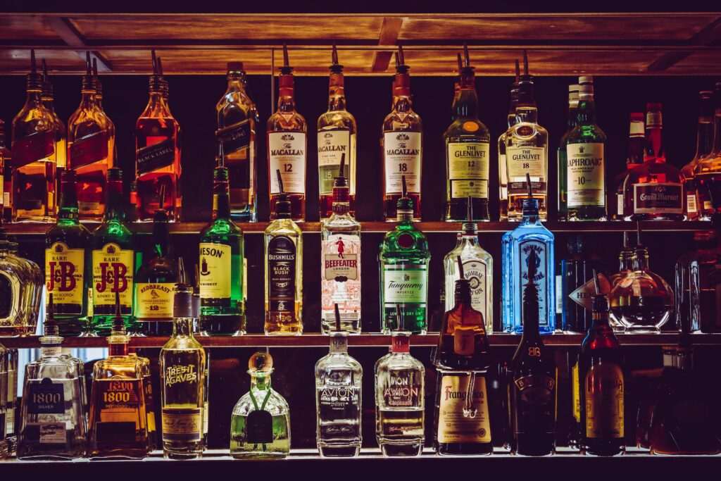 A well-stocked bar shelf featuring various liquor bottles in vibrant colors, creating a warm and inviting atmosphere with a rich, indulgent tone.