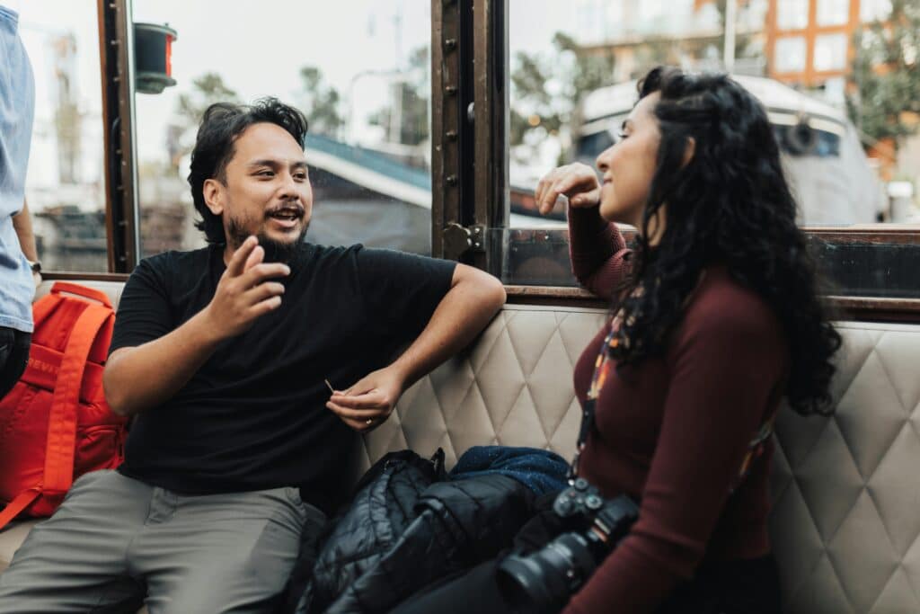 A engaged conversation between two individuals sitting on a boat, surrounded by scenic views outside the windows.
