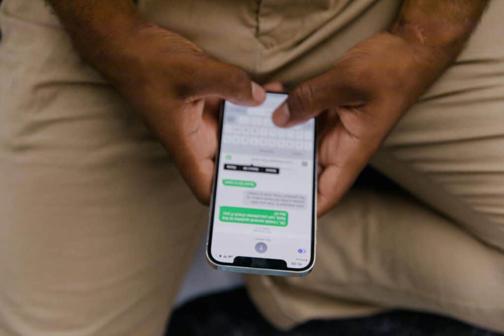 Close-up of hands holding a smartphone, focused on a messaging app display with text conversation visible.