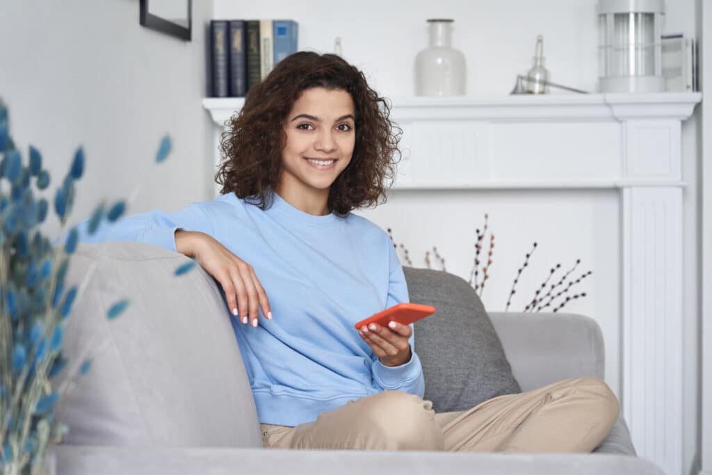women sitting in the couch holding a phone