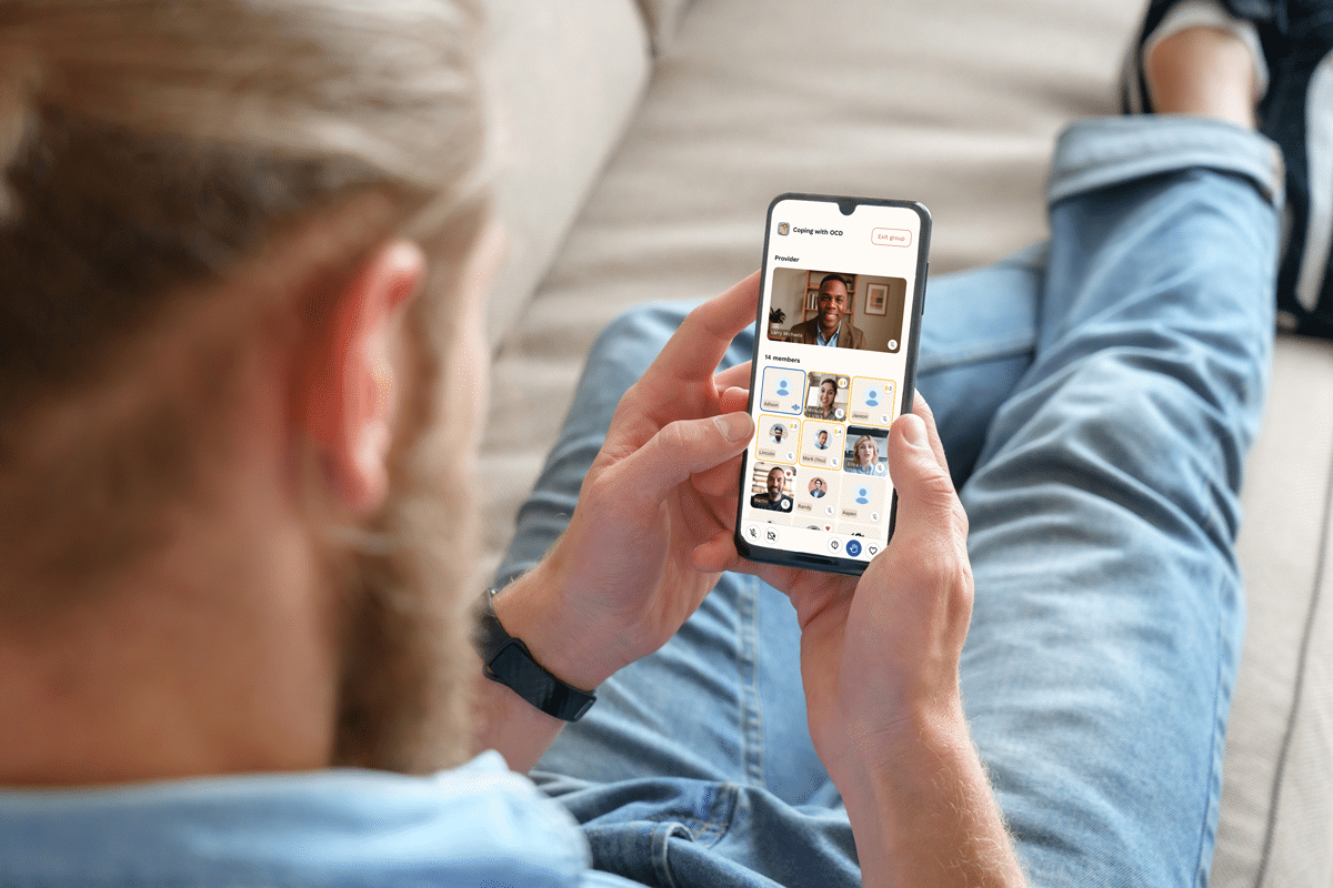 A man sits on a couch, focused on his phone while relaxing in a cozy living room setting